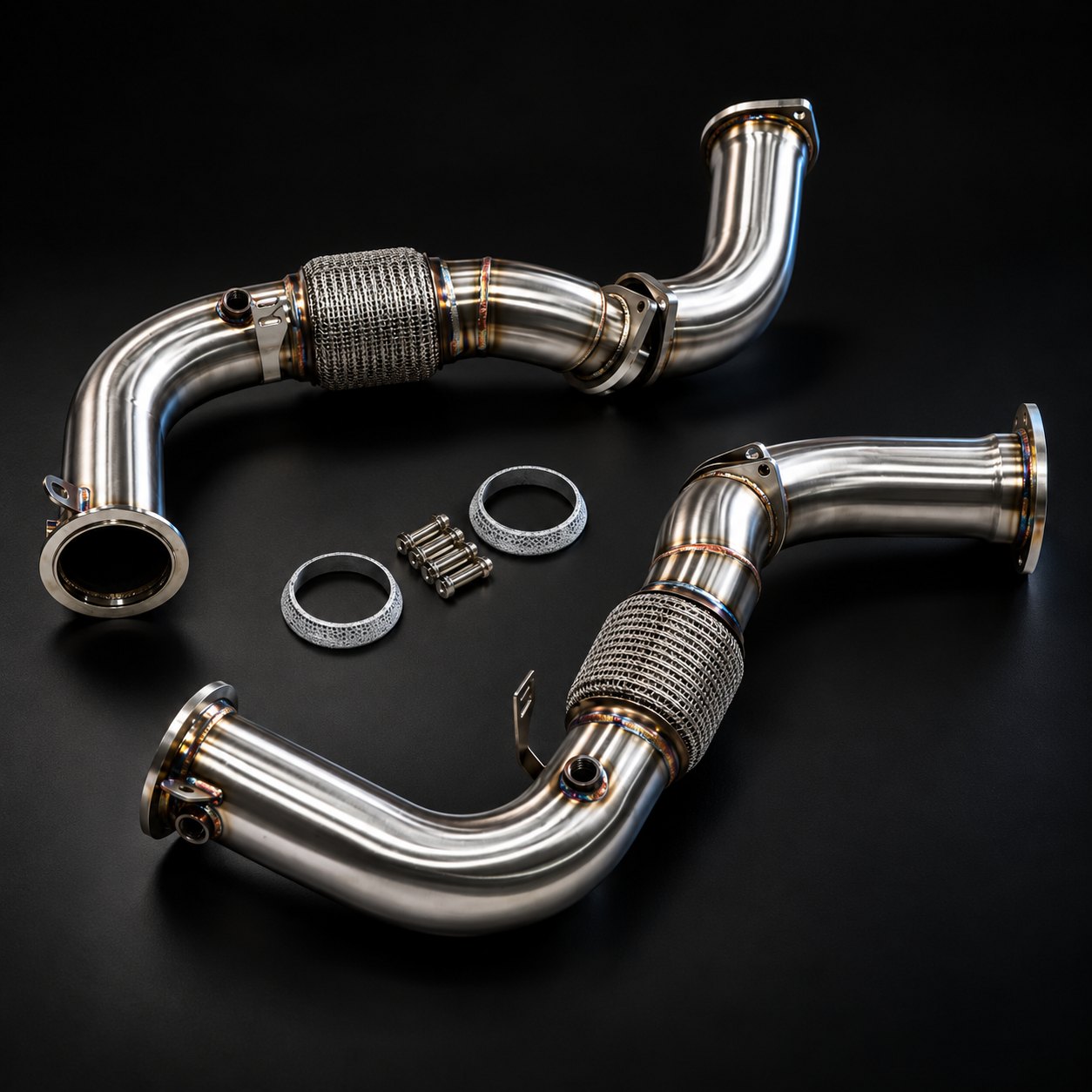 Pair of stainless S68 downpipes with braided flex sections, shown with their gaskets and mounting bolts